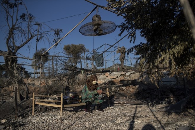 A migrant woman sits on a burned bed in the Moria refugee camp on the northeastern island of Lesbos, Greece, Thursday, Sept....