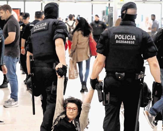 Policisti vlečejo žensko, ki podpira samostojno Katalonijo, s protesta na železniški postaji v Barceloni.