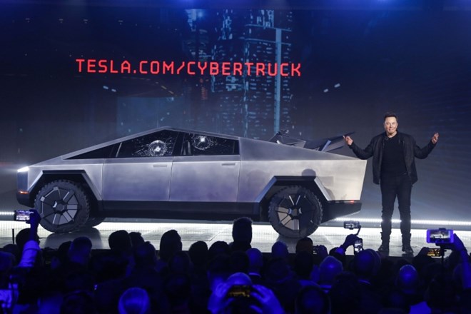 Elon Musk in poltovornjak cybertruck z dvema počenima neprebojnima stekloma.